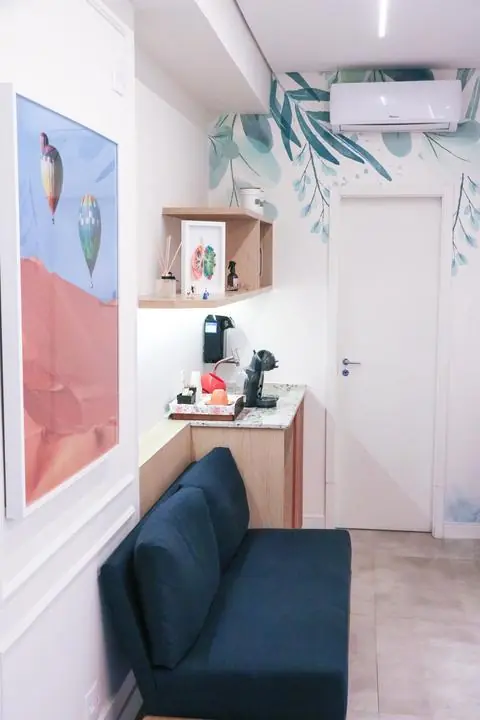 Cantinho do café na sala de espera, com papel de parede de folhas
