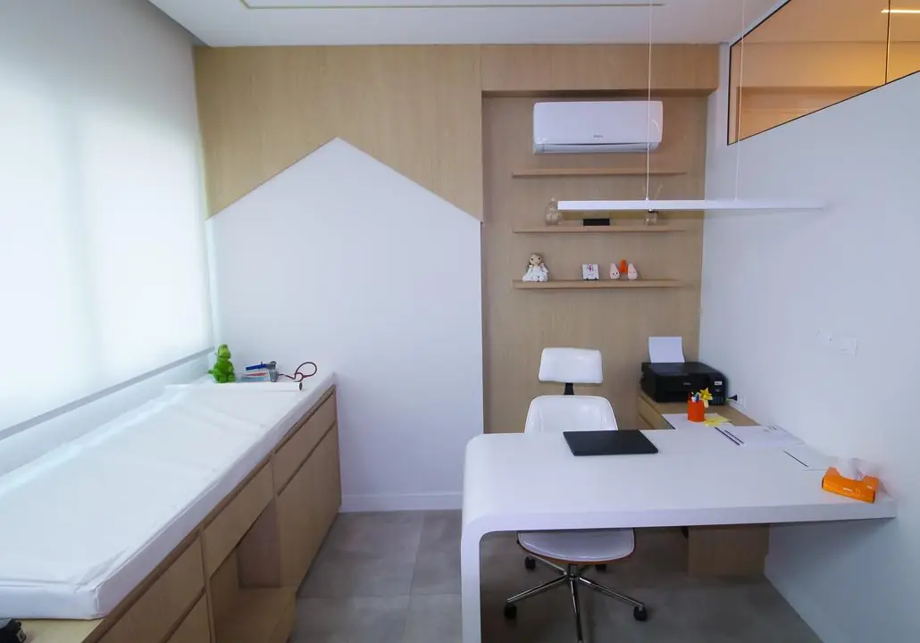 Consultório com mesa de atendimento e maca