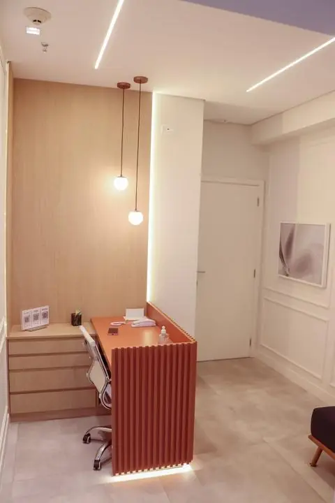 Recepção do consultório, com balcão coral e luminárias pendentes