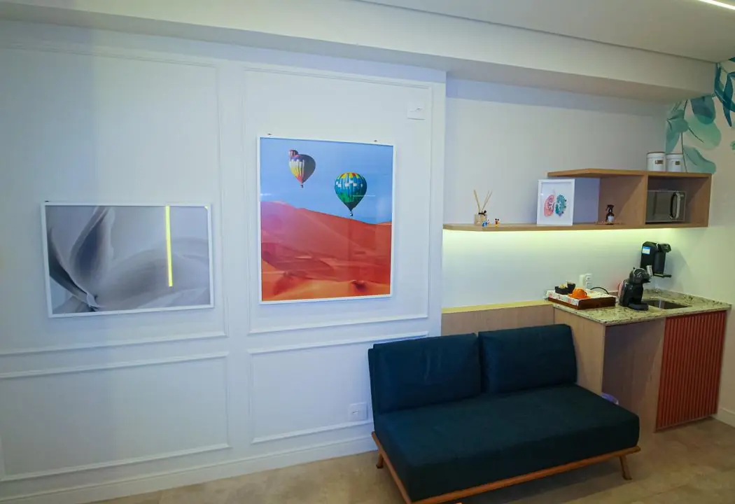 Sala de espera com sofá azul e quadros na parede